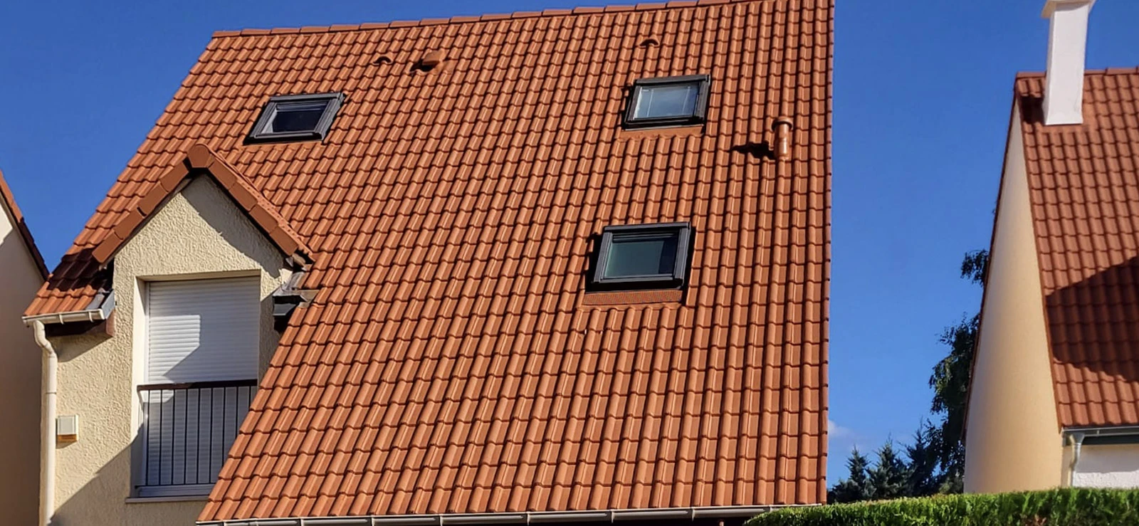 Salon moderne avec canapé d'angle beige, fauteuil vert menthe et pouf assorti. Murs bleu-gris, parquet foncé, grandes fenêtres industrielles noires. Table basse ronde noire, tapis géométrique, lustre sputnik doré suspendu.