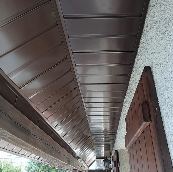 Cuisine moderne avec îlot central et meubles bas anthracite, plan de travail en stratifié imitation bois. Sol en carrelage grand format aspect parquet chêne clair posé en chevrons. Électroménager encastré, crédence carrelage métro blanc. Éclairage LED intégré sous meubles hauts.