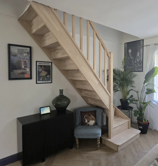 Combles non aménagés avec isolation thermique en laine minérale soufflée au sol. Charpente traditionnelle en bois avec poutres et chevrons apparents. Cloison séparative en plaques de plâtre avec ouverture rectangulaire. Plancher technique sur solives bois recouvert d'isolant en vrac de couleur grise.