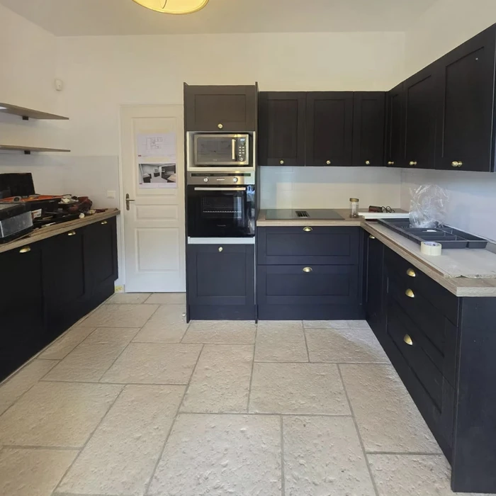 Intérieur résidentiel avec mur blanc et lambris décoratif. Angle de pièce montrant jonction entre mur lisse et boiserie à panneaux rectangulaires surmontée d'une moulure horizontale. Plafond avec corniche d'angle visible.