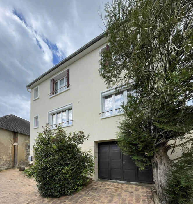 Façade contemporaine de maison individuelle moderne avec architecture géométrique bi-ton. Murs enduit beige et gris anthracite, baies vitrées rectangulaires à châssis noir, volets roulants aluminium. Rez-de-chaussée avec parement pierre naturelle grise, colonnes structurelles, toiture terrasse étanchée membrane EPDM.